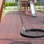 Nestschaukel (BNS 90 cm) aus schwarzem Netzseil auf modernem Spielplatz mit Klettergerüst und Rutsch