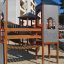Zitadelle Spielplatz mit Spieltürmen und Spiralrutschen auf Sandboden, städtischer Hintergrund.