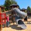 Zitadelle Spielplatz mit Spieltürmen und Spiralrutschen, Kind auf Rutschbahn.