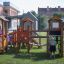 Kinder spielen auf einem Alpha Barrierefreie Spielplatz mit Rutschen und Klettergerüsten.