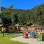 Barrierefreier Alpha Spielplatz mit Rutschbahn und Spielhäusern im Freien.