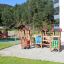 Barrierefreier Spielplatz Alpha mit Holzspielgeräten und Rutsche im Außenbereich.
