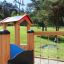 Barrierefreier Spielplatz Alpha mit Holzelementen und buntem Dach im Park.