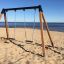 Doppelt Schaukel mit zwei Sitzen am sandigen Strand mit Blick auf das Meer.