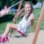Kinder spielen auf einer Doppelt Schaukel im Park.