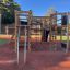 Spielplatzgerät Axel Kletteranlage mit Kletterwand auf rotem Untergrund im Freien.