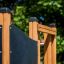 Teil einer Axel Kletteranlage mit Holzpfosten und schwarzer Kletterwand im Freien