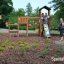 Kinder spielen auf einem Triangle Spielturm mit Rutsche und bunten Ballons im Park.