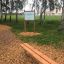 Lärchenholz-Bank im Park mit Infotafel und Kiesweg.