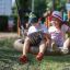 Zwei Kinder lesen gemeinsam ein Buch auf einem Nature Swing Frame BNS+1 im Park