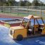 Kinder-Sandkasten in Form eines gelben und roten Lastwagens auf einem Spielplatz.