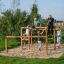 Kinder spielen auf einem Over–under Klettergerüst im Freien.