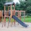 Eragon Spielanlage mit Tunnel und Rutsche auf einem Spielplatz aus Holz.