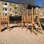 Holzspielplatz Eragon Spielanlage mit Tunnel und Rutsche in einem Sandbereich.