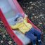 Kleiner Junge rutscht auf einer roten Rutsche im Spielplatz.