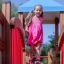 Fröhliches Mädchen spielt auf Herausforderung II Spielanlage mit Spielturm und Rutsche in rosa Kleid
