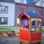 Kind im bunten Spielhaus auf einem Spielplatz.