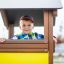 Lächelnder Junge im Spielhaus auf einem Spielplatz.