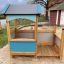 Holzspielhaus mit Veranda und Sandkasten auf einem Spielplatz.
