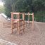 Holz-Klettergerüst Kaukasus Klettergerüst auf einem Spielplatz mit Rutsche im Hintergrund.