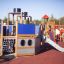 Dampfer-Spielplatzgerät mit Rutsche und Kletterelementen auf einem Außenspielplatz.