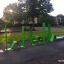 Grünes Outdoor-Fitnessgerät Stahlband Fitness II in einem Park bei Sonnenaufgang.