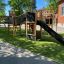 Herausforderung II Spielanlage mit Rutsche auf einem Spielplatz mit grünem Kunstrasen.