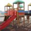 Buntes Kinderspielgerät mit Rutsche und Klettertürmen auf dem Spielplatz.