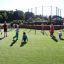 Kinder spielen Fußball auf Multiarena aus Holz.