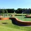 Holz-Multiarena auf einem Freizeitsportplatz mit Basketballkörben und wellenförmigen Böden.