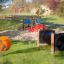 Fledermaus Federwippe auf einem Kinderspielplatz mit Rutschen und Klettergerüsten im Hintergrund
