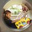 Mädchen spielt in einem Tunnel mit einem gelben Spielzeugbus.