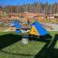 Blaues Jet Federwippe Spielgerät auf grünem Kunstrasen in einem Outdoor-Spielplatz.
