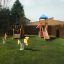 Lokomotive Spielhaus für Kinder mit Rutsche, Schaukeln und Kletterturm auf grünem Rasen.