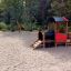 Lokomotive Spielhaus auf Spielplatz mit Rutsche und Schaukeln im Hintergrund
