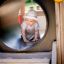 Kleinkind kriecht durch ein Tunnelrohr im Lokomotive Spielhaus auf einem Spielplatz.