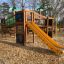 Dschungelcamp Klettergerüst mit Rutsche und bunter Dekoration auf einem Spielplatz