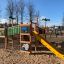 Dschungelcamp Klettergerüst mit Rutsche auf einem Spielplatz mit Sandboden.
