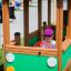 Mädchen spielt in einem bunten Bus Spielhaus mit Lenkrad.