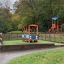 Kinder-Spielhaus im Bus-Design auf einem Spielplatz, umgeben von Grün.
