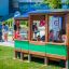 Kinder spielen im Bus Spielhaus auf einem sonnigen Spielplatz.