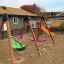 Grüner Schaukelsitz: All Access Seat auf einem Kinderspielplatz, umgeben von weiteren Spielgeräten.