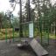 Informationstafel NAF MEDIUM auf einem Spielplatz im Wald mit Rutsche und Klettergerüst.