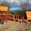 Holzspielhaus Lasses Spielhaus mit Rutsche auf Sandplatz unter blauem Himmel.