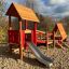 Lasses Spielhaus mit Rutsche und Sandkasten auf einem Spielplatz.