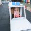 Kleines Mädchen spielt Fahrerin in einem Krankenwagen Spielhaus auf einem Spielplatz.