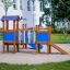 Kastell Spielturm mit Rutsche und farbenfrohen Elementen auf einem Spielplatz.