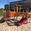 Holzspielplatz Kastell Spielturm mit Rutsche und Kletterwand auf Sandboden.