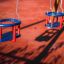 Zwei Doppel Baby Schaukeln aus Kunststoff, rot und blau, auf einem Spielplatz.