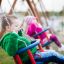 Kinder schaukeln auf einem Doppel-Babyschaukel im Park.